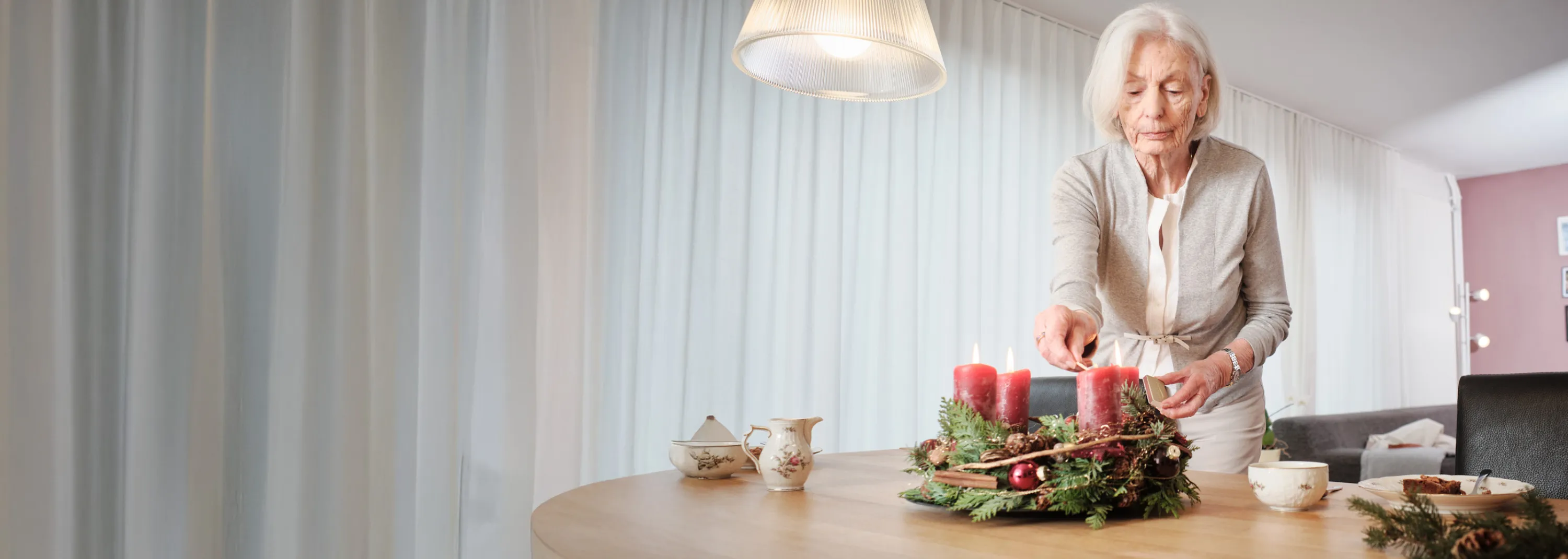 Signora anziana accende le candele della corona dell’Avvento.