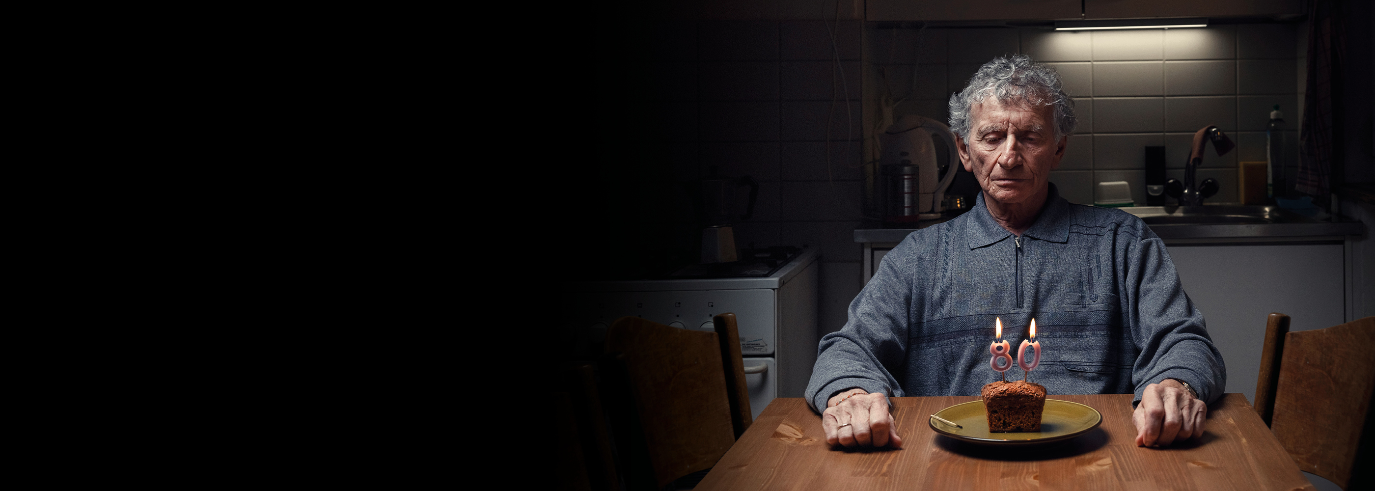 Ein einsamer älterer Herr vor einem Stück Geburtstagskuchen